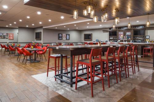 a restaurant with a bar with red stools at Holiday Inn Auburn-Finger Lakes Region, an IHG Hotel in Auburn