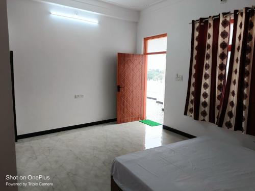 Cette chambre comprend un lit, une porte et une fenêtre. dans l'établissement Jamnagar Hills resort, à Udaipur
