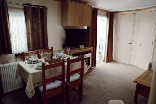 a dining room with a table and chairs and a kitchen at Melrose in Leysdown-on-Sea