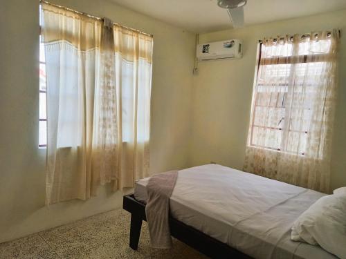 um quarto com uma cama e uma janela com cortinas em Dado's Place em Calibishie