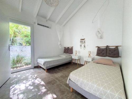Schlafzimmer mit einem Bett und einem Fenster in der Unterkunft cannelle in Sainte-Anne