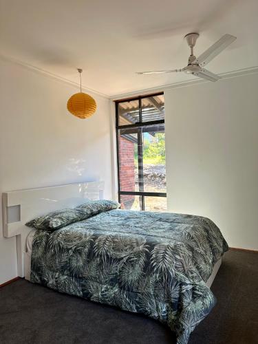 een slaapkamer met een bed en een plafondventilator bij Tranquil home in hills with city views 