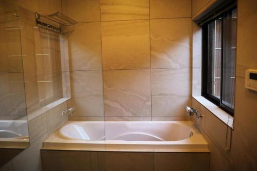eine große Badewanne im Bad mit Fenster in der Unterkunft 一吾山房 in Kyoto