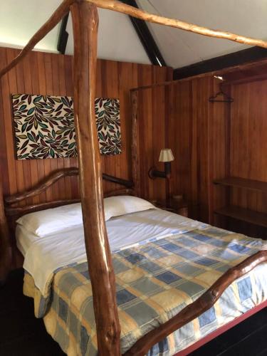 een slaapkamer met een houten bed met een hemelbed bij Gad Gha Kum - El mensajero Lodge in San Ramón