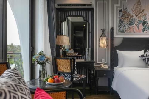 a bedroom with a bed and a table with fruit on it at Serene Nature Hotel & Spa in Hoi An