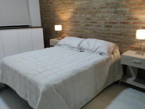 Un dormitorio con una cama y una pared de ladrillo. en Casa Isabel - Villa Nueva - Villa María, en Villa María
