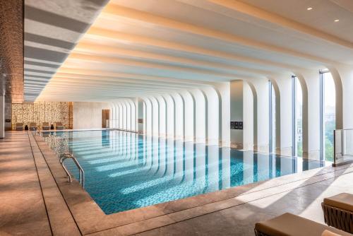 a large swimming pool in a building with windows at Grand Mercure Yichang Waitan in Yichang