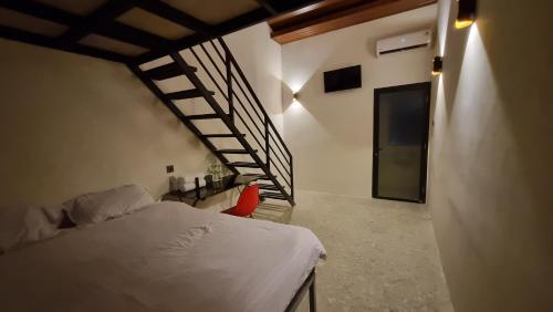 a bedroom with a bed and a spiral staircase at Uni Inn Semarang - Gunung Pati in Semarang