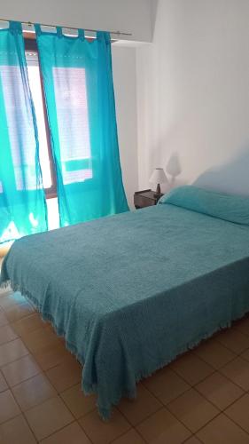 1 dormitorio con 1 cama con cortinas azules y ventana en El Dorado Deptos a una cuadra del mar en San Bernardo