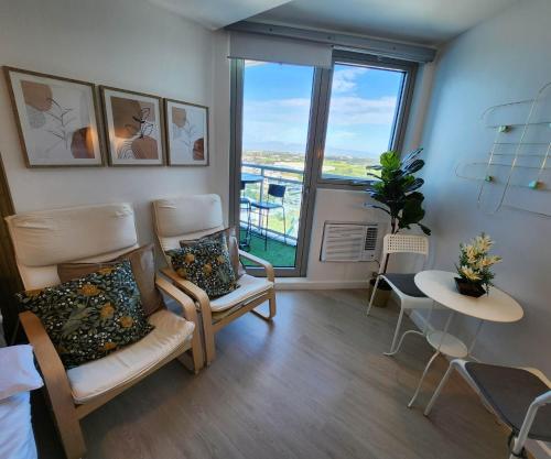 uma sala de estar com duas cadeiras e uma grande janela em Cozy Condo with City View em San Fernando