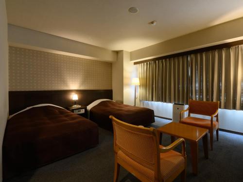 Sabae的住宿－Sabae City Hotel，酒店客房带两张床和一张桌子以及椅子。