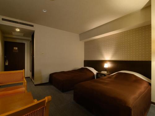 a hotel room with two beds and a chair at Sabae City Hotel in Sabae