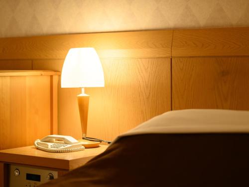 a bed room with a phone and a lamp on a table at Sabae City Hotel in Sabae