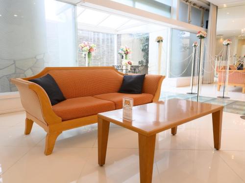 a living room with an orange couch and a coffee table at Sabae City Hotel in Sabae
