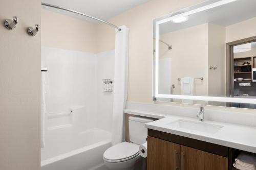 a bathroom with a sink and a toilet and a mirror at Candlewood Suites Sioux Falls by IHG in Sioux Falls