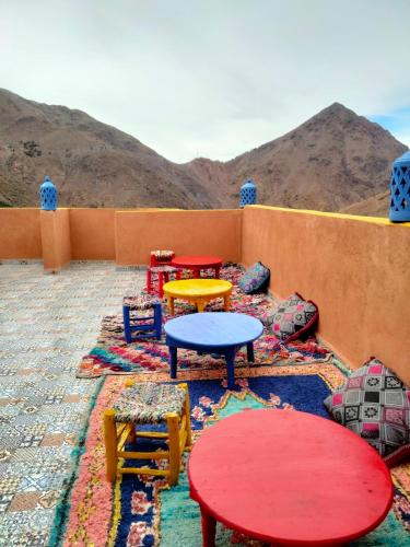 a room with colorful tables and chairs with mountains in the background at Riad imNane Lodge in Tamguist
