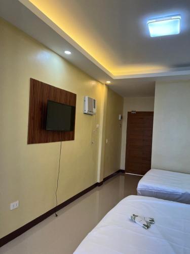 a hotel room with two beds and a flat screen tv at C View Resort in Sipalay