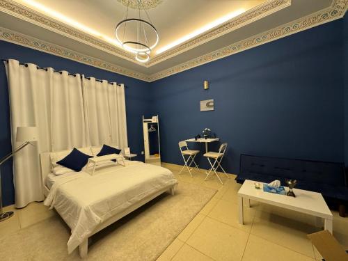 Dormitorio azul con cama y mesa en Private room in the heart of Dubai with Burj Khalifa view, en Dubái