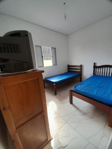 een kamer met een bed, een tv en een bank bij Casa do Enzo in Peruíbe