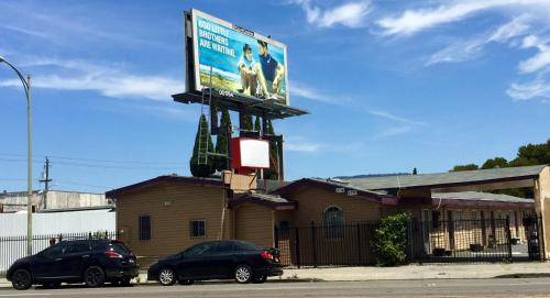 zwei Autos, die vor einem Gebäude mit einer Plakatwand geparkt werden in der Unterkunft International Casa Hotel in Oakland