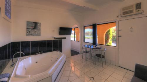 baño grande con bañera y mesa en Twin Swans Motel en Inverell