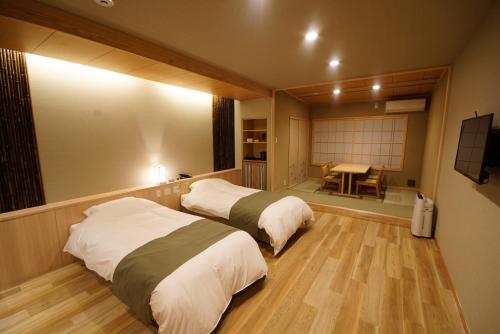 a room with two beds and a table in it at 京ごはんと露天風呂の宿 ゆのはな 月や 