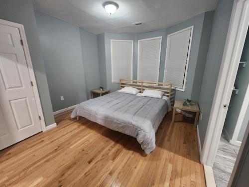 a bedroom with a bed with blue walls and wooden floors at Mins to NYC, Cosy 3 Bedroom Apartment in Jersey City