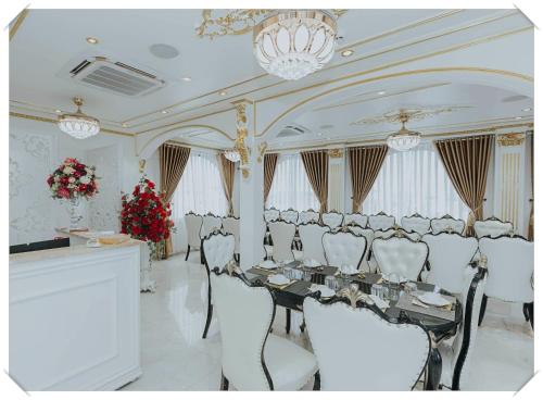 a banquet room with a long table and white chairs at Hoàng Gia Hotel Tuy Hoà in Tuy Hoa