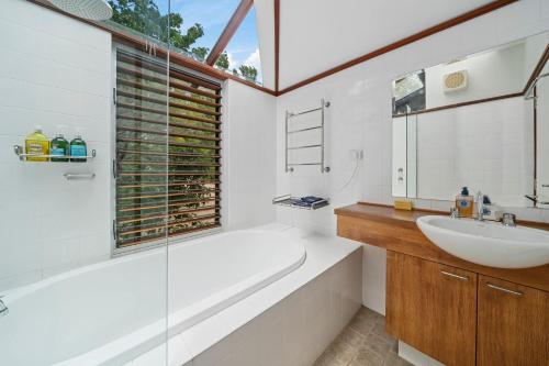 a bathroom with a tub and a sink and a mirror at Summer House in Wentworth Falls