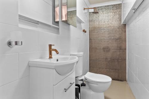 a white bathroom with a toilet and a sink at HAZE18 - Sunny Shorefront Retreat Uninterrupted Ocean Views in Quinns Rocks