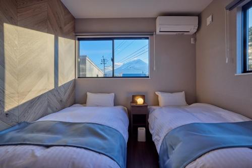 two beds in a small room with a window at 富士ガーデンビュー　空と庭と in Fujikawaguchiko