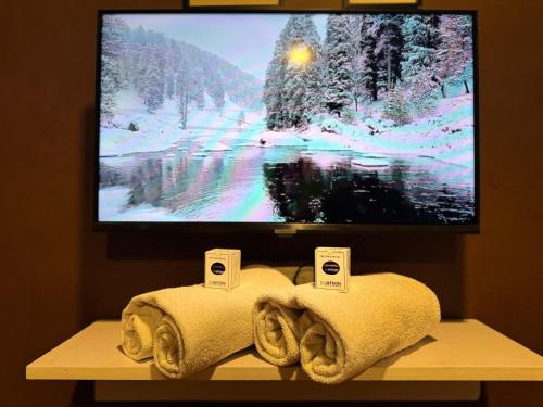 een flatscreen-tv bovenop een tafel met handdoeken bij Hotel Jafson Accommodates in Srinagar