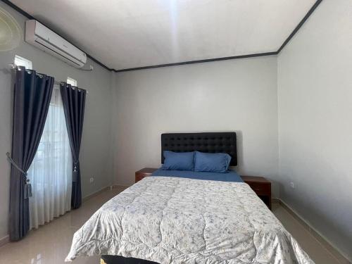 sypialnia z łóżkiem z niebieską pościelą i oknem w obiekcie Sumbawa Maluk Homestay Kost tika w mieście Maluk