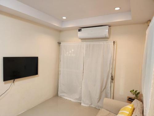 a living room with a television and a window at HOMEis Villa Sattahip in Ban Tao Than