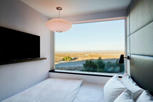 a bedroom with a window with a bed and a television at citizenM Menlo Park in Menlo Park