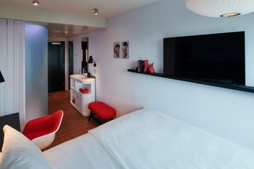 a room with a bed and a tv and a red chair at citizenM Menlo Park in Menlo Park
