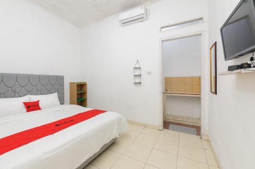 1 dormitorio con 1 cama grande y TV en RedDoorz Syariah near Institut Darmajaya Lampung, en Bandar Lampung