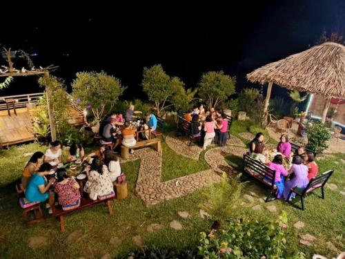 a group of people sitting on benches in a garden at Zoni Home Trạm Tấu in Cham Ta Lao