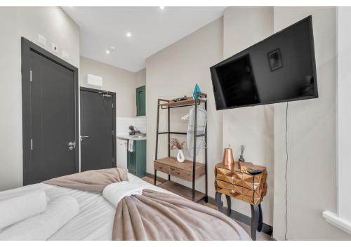 1 dormitorio con 1 cama y TV de pantalla plana en Escape the Ordinary: Cozy and Charming Studio, en Londres