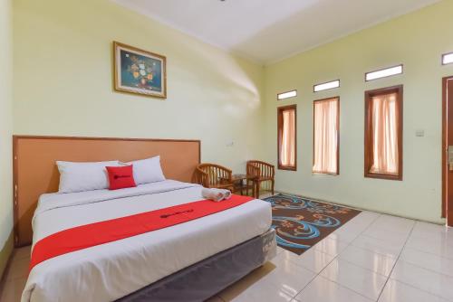 a bedroom with a large bed with a red blanket at RedDoorz At Pondok Winagung Ciwidey in Ciwidey