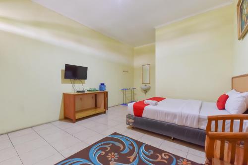 a bedroom with a bed and a tv in it at RedDoorz At Pondok Winagung Ciwidey in Ciwidey