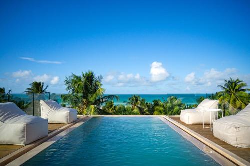a swimming pool with two lounge chairs and the ocean at Mero Mero Hotel in El Cuyo