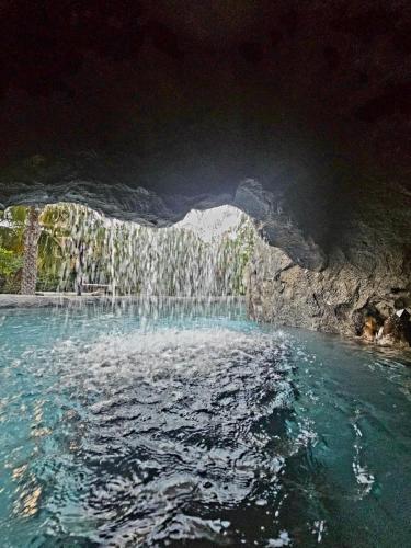 a pool of water in a cave with a waterfall at Balu Retreat Center in Playa Junquillal