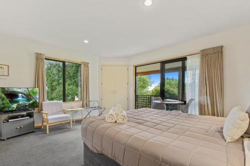 a bedroom with a large bed and a living room at Alpine Garden Motel in Hanmer Springs