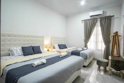 a bedroom with two beds and a television on the wall at Bisma Balcony Homestay in Jetis