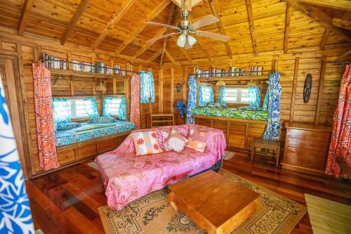 una sala de estar con sofá y 2 camas en una cabaña en Heimanarii,slodge Manu, en Haapiti