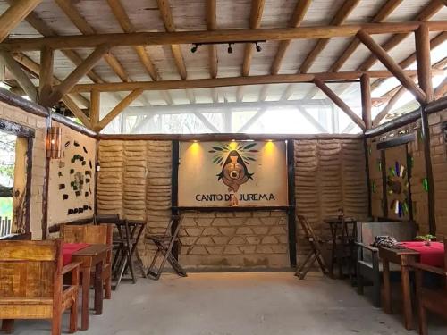 コルンバウにあるCanto de Jurema Corumbau Glamping, Chalé, Acolhimento e Sustentabilidadeのテーブルと壁に看板が備わる広い客室です。