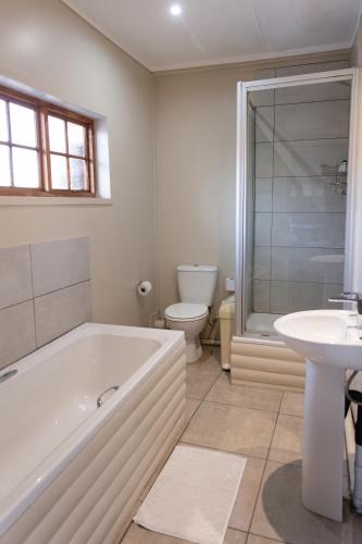 a bathroom with a tub and a toilet and a sink at Riverside Lodge & Conference Center in Aliwal North