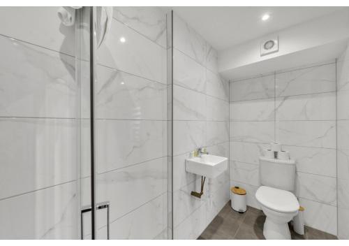 a white bathroom with a toilet and a shower at The Wanderlust Studio: Travelers' Haven in London