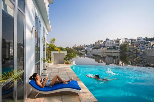 two women laying in a swimming pool next to a building at Moustache Udaipur Verandah in Udaipur